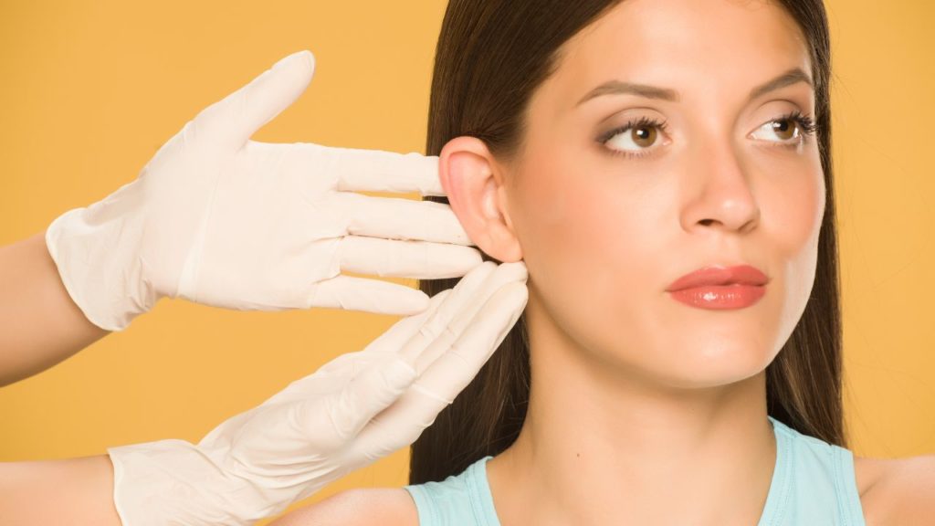 Doctor's hands touching the nose of a young woman